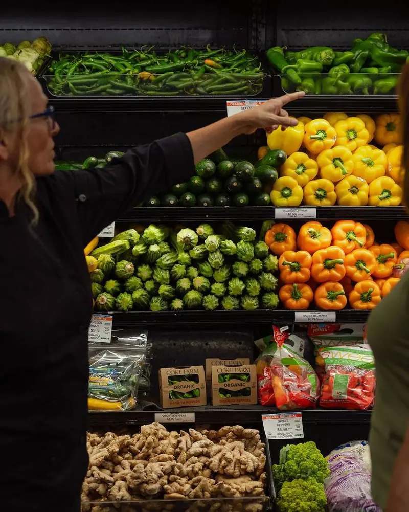 A PFC chef showing a guest how to choose produce at a grocery store