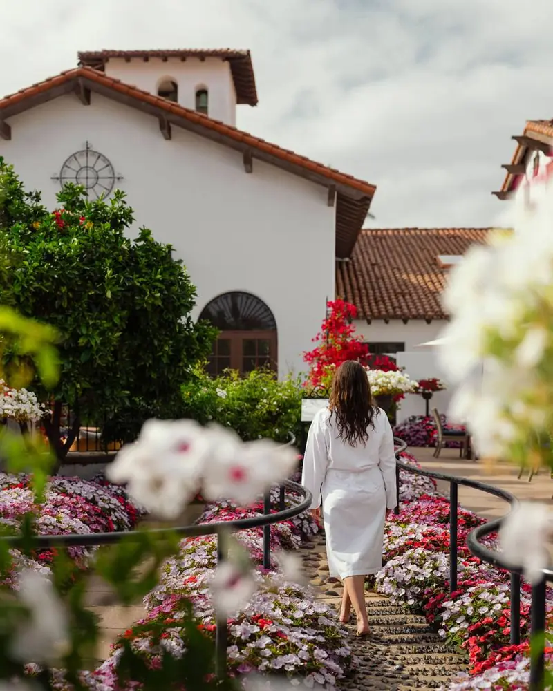 A guest in a robe walking through the flower gardens at the Omni La Costa