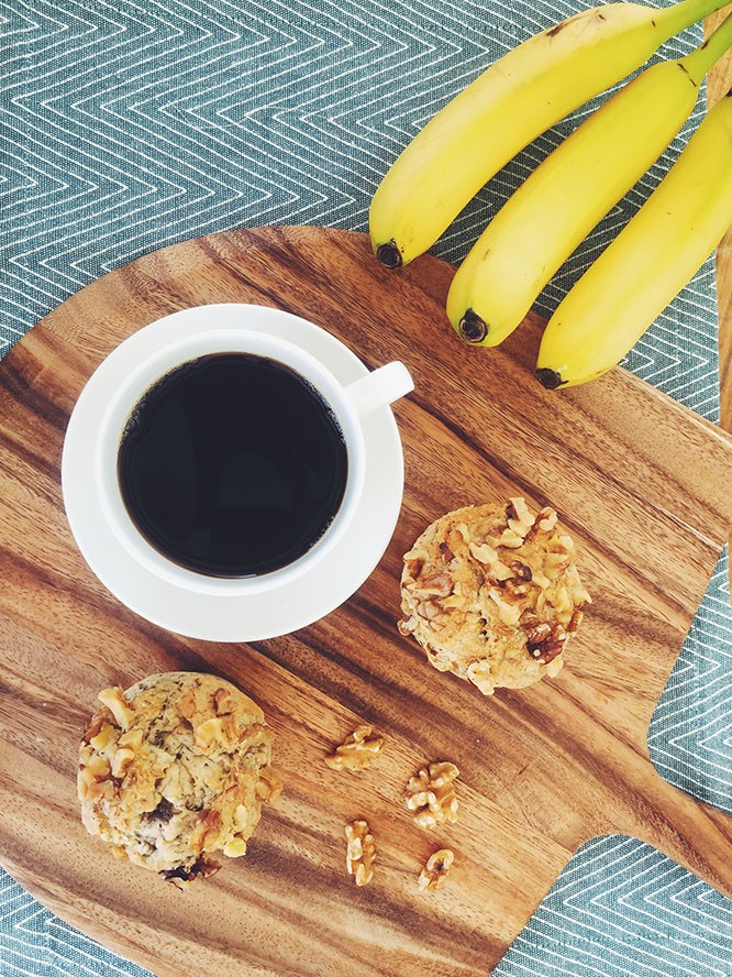 Gluten free banana muffins displayed on cutting board with coffee and bananas