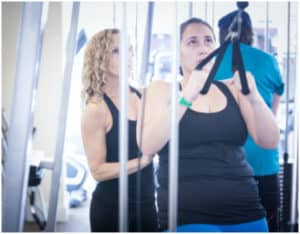 personal trainer helps woman to practice high rows and lose weight