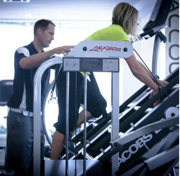 Personal trainer works with woman on climbing machine for wellness purposes