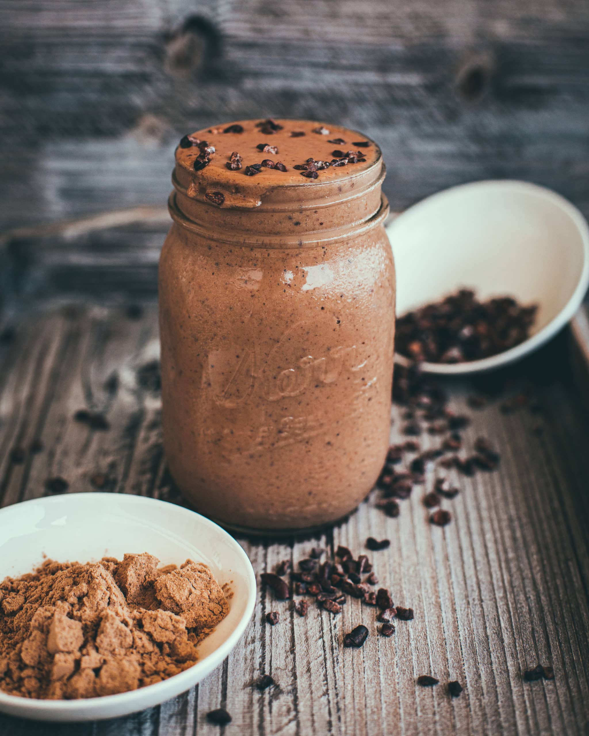 Chocolate smoothie with cacao nibs on top in a mason jar on a table