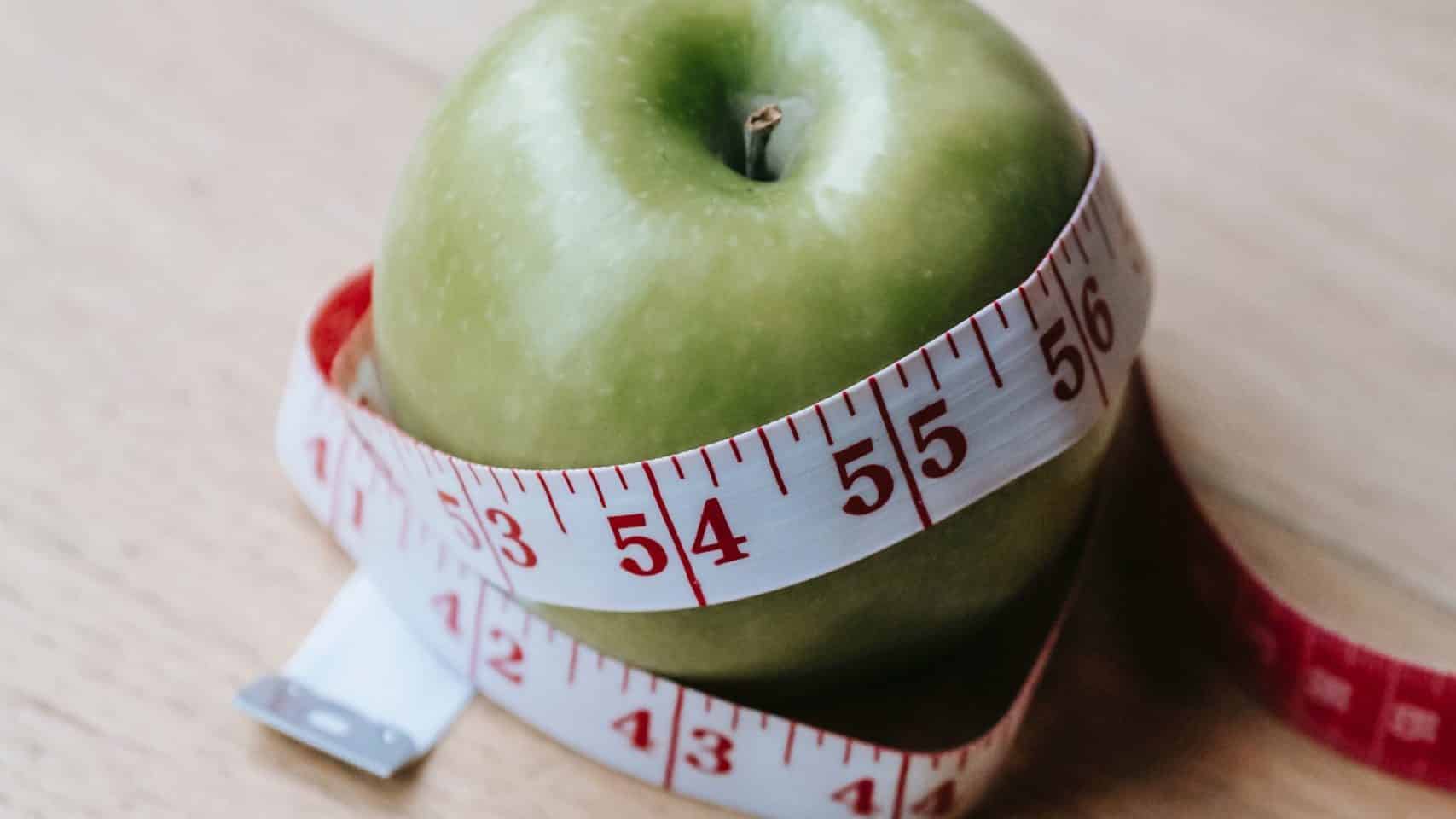 green apple with measuring tape wrapped around twice