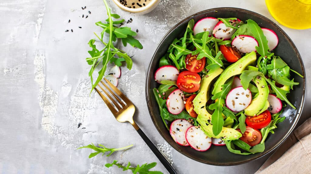 healthy salad with tomatoes and avocados in a bowl on a table