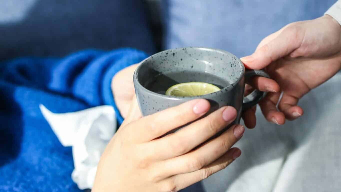 hands holding cup with tea and lemon