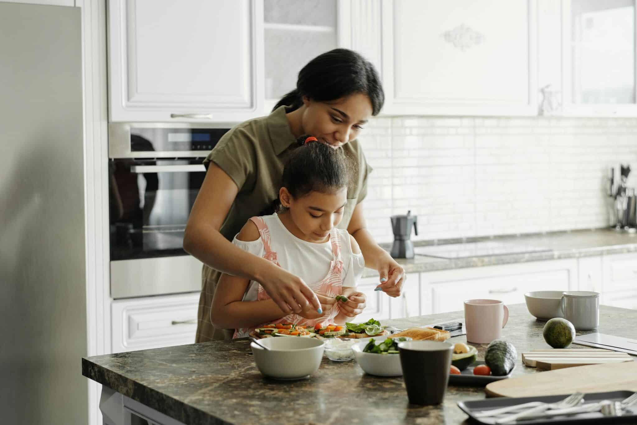 Photo of mother teaching daughter a sustainable nutrition meal in the kitchen.
